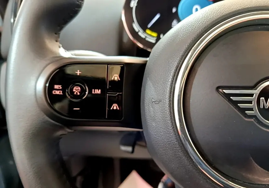 Gros plan sur le volant cuir noir du MINI COUNTRYMAN Cooper SE avec commandes de régulateur adaptatif côté gauche.