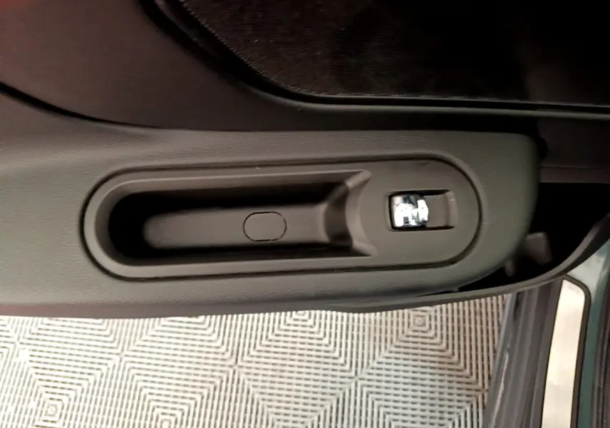 Poignée intérieure de porte côté conducteur du MINI Countryman vert 2023, avec bouton de verrouillage chrome.