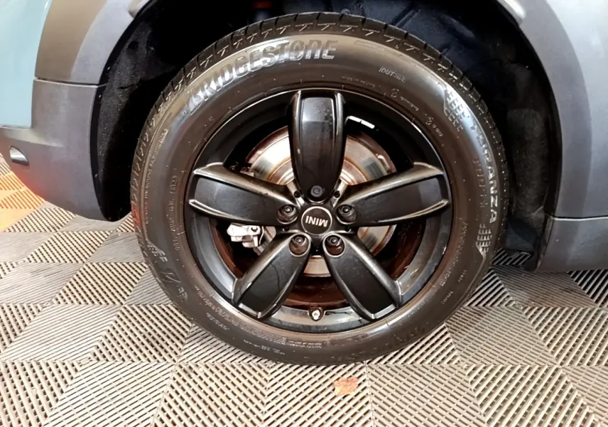 Gros plan sur la roue avant gauche noire avec jante cinq branches du MINI Countryman vert hybride 2023.