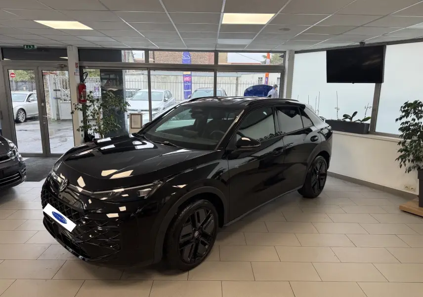 Volkswagen T-Roc noir intense en 3/4 avant droit, avec jantes noires et intérieur visible en showroom.