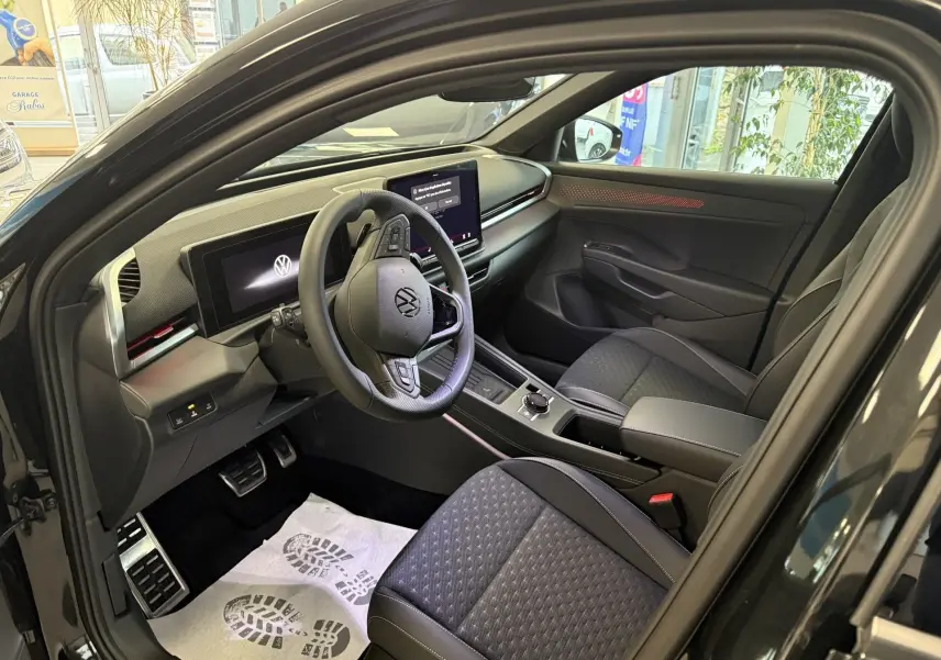 Vue intérieure côté conducteur du Volkswagen T-Roc noir intense 2026, avec tableau de bord numérique et sellerie tissu noire.