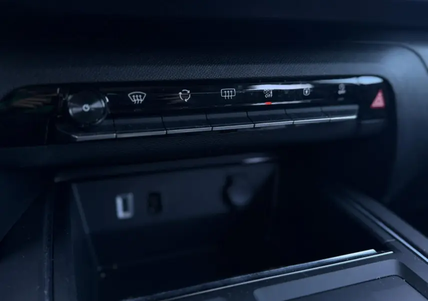 Détail du tableau de bord noir du Citroën C5 Aircross Hybrid 2025 montrant la rangée de commandes climatisation et prises USB.