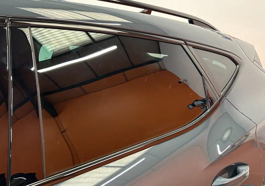 Gros plan sur la vitre arrière côté droit de la CUPRA Formentor bleu Fjord métal avec reflet de l'éclairage intérieur.