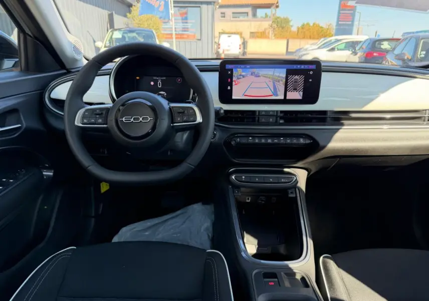 Vue intérieure avant du tableau de bord de la Fiat 600 T-Gen 3 blanc avec écran tactile et volant multifonction.