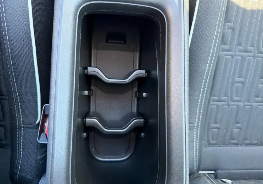 Gros plan sur le rangement central noir entre les sièges avant d'une Fiat 600 T-Gen 3 blanche, intérieur tissu gris.