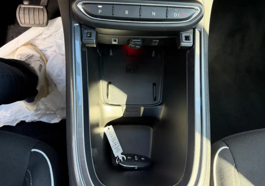 Vue plongeante sur la console centrale noire de la Fiat 600 T-Gen 3 blanche avec clé et sélecteur de boîte auto visible.