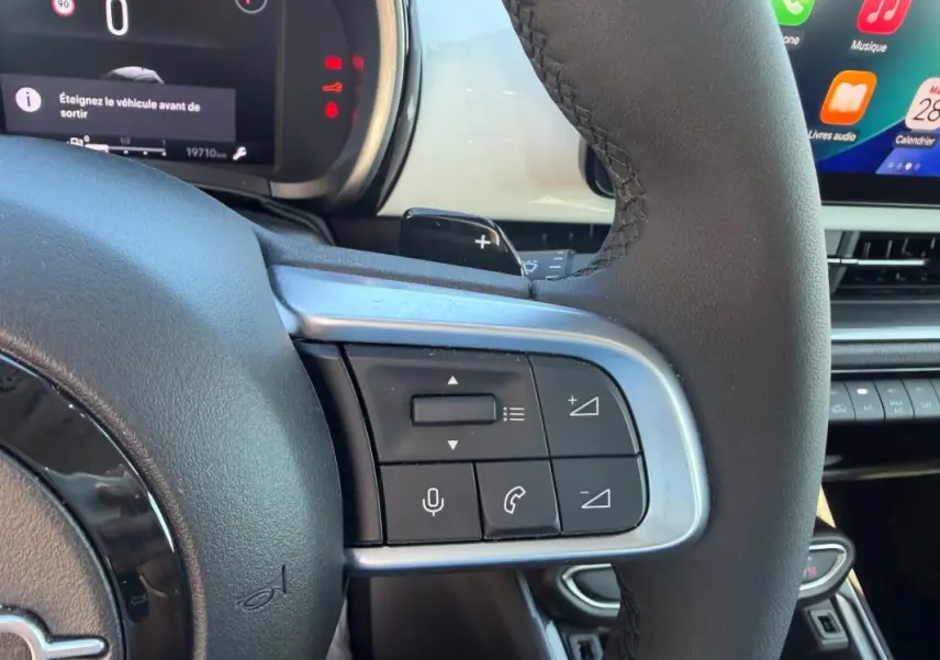 Gros plan sur la partie droite du volant noir de la Fiat 600 T-Gen 3 blanc, avec commandes audio et téléphone visibles.