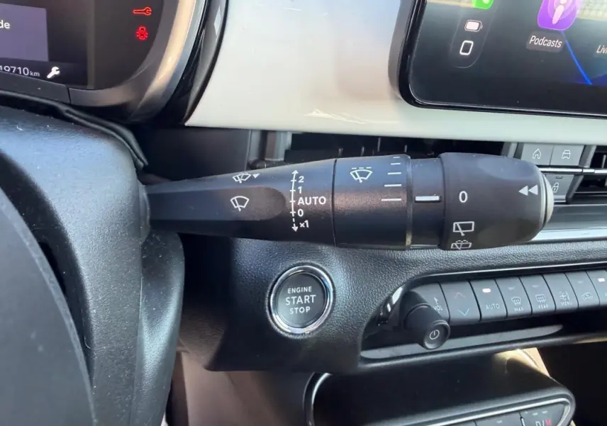 Gros plan sur la commande d’essuie-glace et le bouton start/stop du tableau de bord intérieur d’une Fiat 600 blanche.