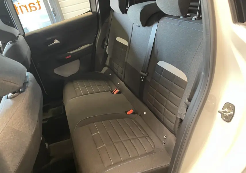Vue intérieure côté droit sur la banquette arrière tissu noir avec appuie-têtes et ceintures d’une Citroën C3 blanche.