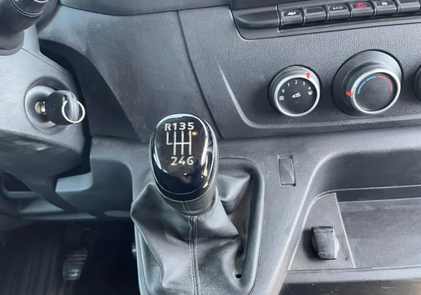 Gros plan sur levier de vitesses manuel noir et commandes de climatisation du tableau de bord d'un Renault Master blanc 2020.