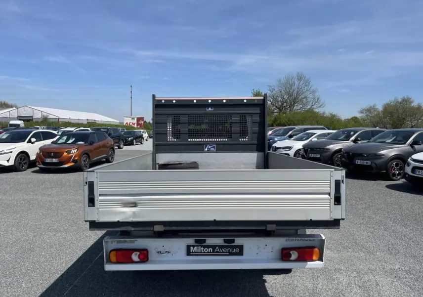 Vue arrière d'un Renault Master blanc avec plateau ridelles aluminium et cabine double sur un parking.