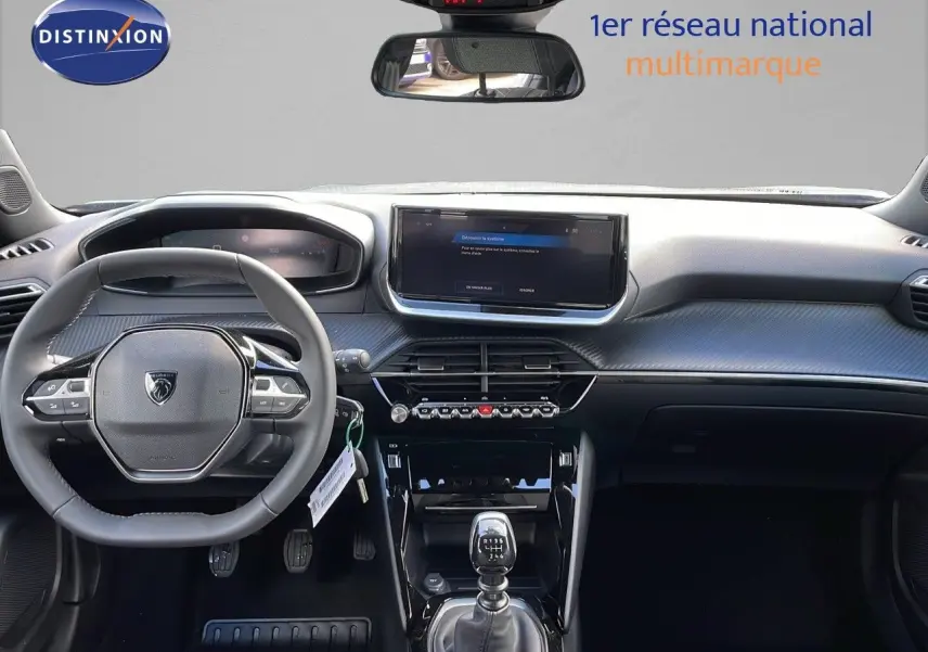 Intérieur Peugeot 2008 2025 vue de face, tableau de bord gris avec volant compact et boîte manuelle visible.