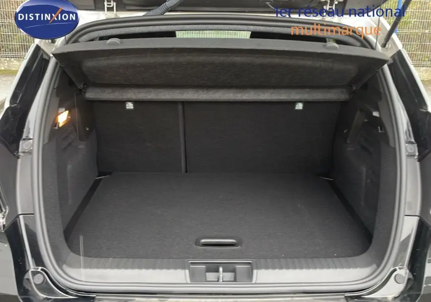 Coffre ouvert d'un Renault Captur E-Tech hybride noir étoile métal avec toit beige, vue arrière montrant l'espace de chargement.