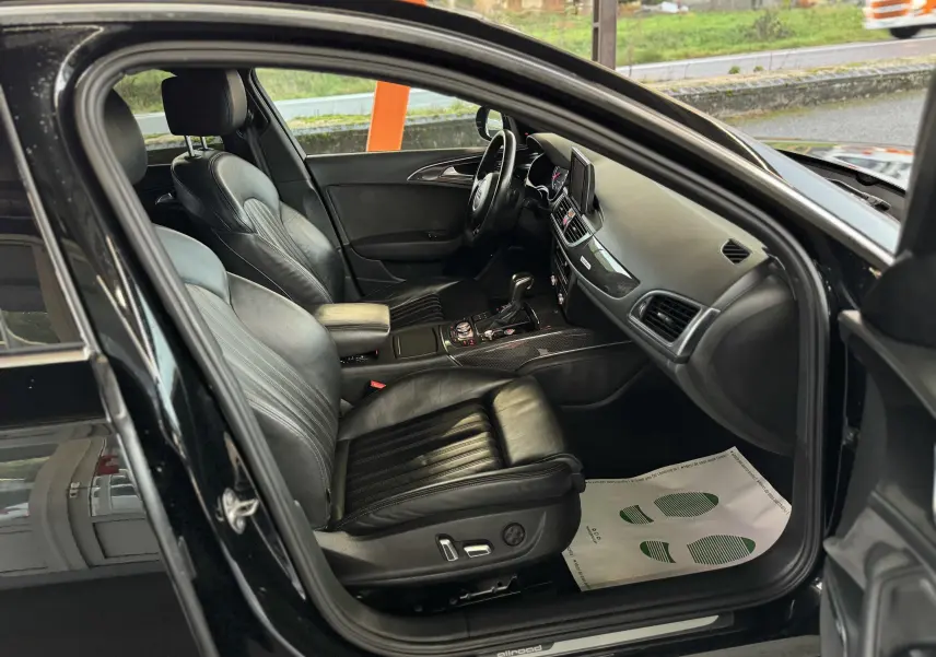 Vue intérieure côté conducteur d'une Audi A6 Avant Allroad noire de 2016, avec sièges cuir noir et tableau de bord moderne.