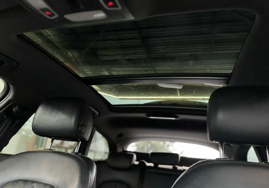 Vue intérieure arrière montrant les appuie-têtes en cuir noir et le toit ouvrant panoramique de l'Audi A6 Avant Allroad 2016.