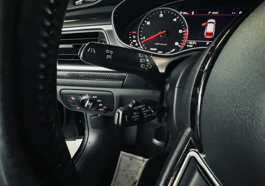 Gros plan sur le tableau de bord noir de l'Audi A6 Allroad, avec commandes au volant et affichage digital du compteur.