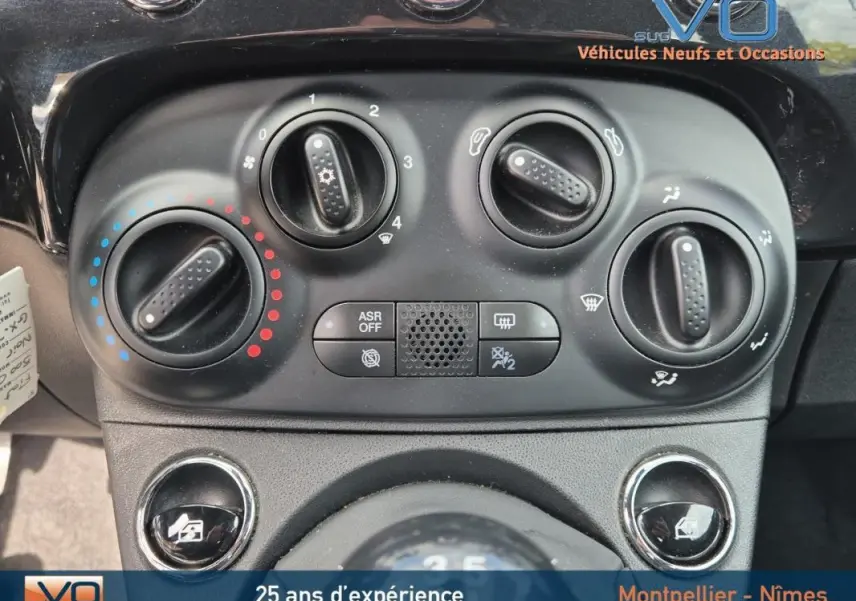 Gros plan sur les commandes de climatisation et ventilation du tableau de bord du Fiat 500C noir 2024 hybride.