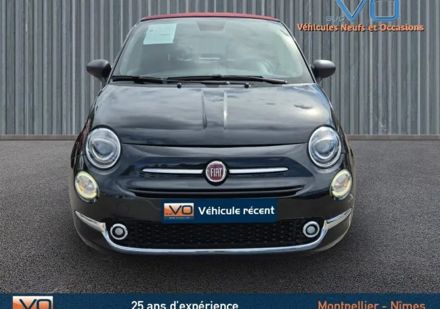 Vue frontale d'une FIAT 500C noire 2024 avec toit rouge, affichant ses phares ronds et la calandre chromée.