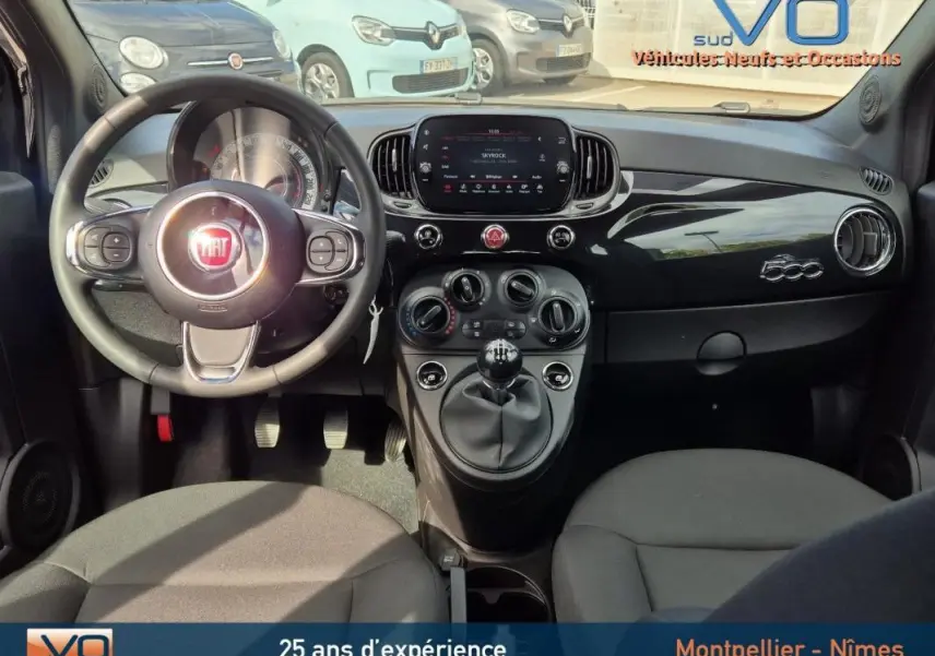 Intérieur avant de la FIAT 500C noire 2024, tableau de bord brillant avec logo 500 et volant multifonction.