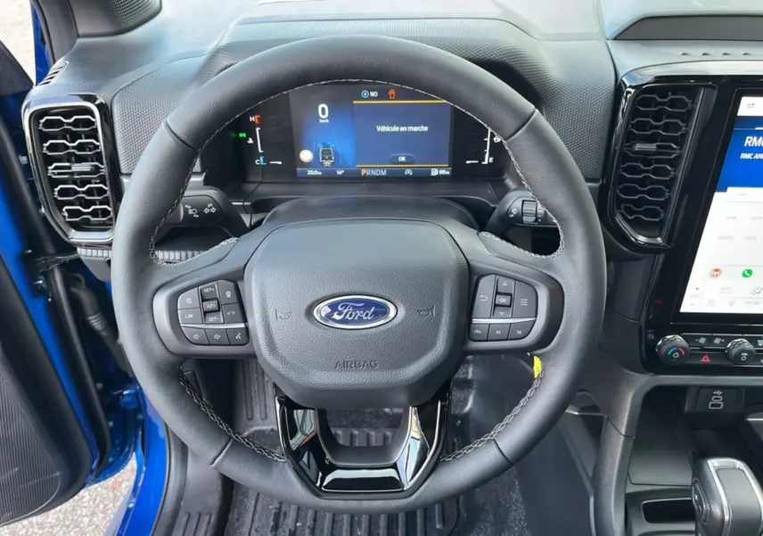 Vue rapprochée du volant cuir multifonctions et tableau de bord numérique du Ford Ranger bleu lightning 2025.