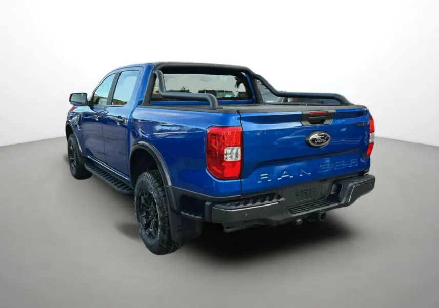 Vue 3/4 arrière du Ford Ranger bleu lightning avec arceaux noirs et attelage visible sur fond neutre.