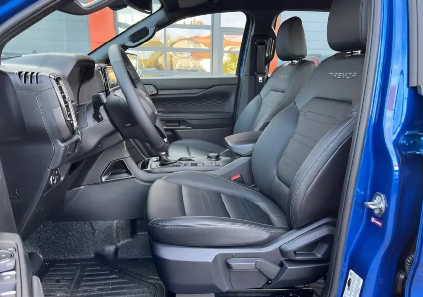 Intérieur côté conducteur du Ford Ranger 2025 bleu lightning, sièges en cuir noir avec logo Tremor brodé.