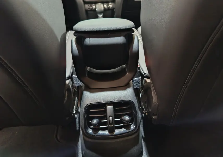 Détail de la console centrale arrière avec aérateurs, entre les sièges noirs d'une MINI Countryman blanche.