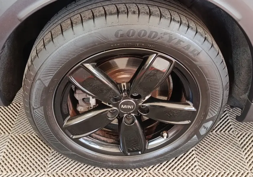 Gros plan sur la roue avant droite noire brillante d'une MINI Countryman blanche, avec pneu Goodyear visible.