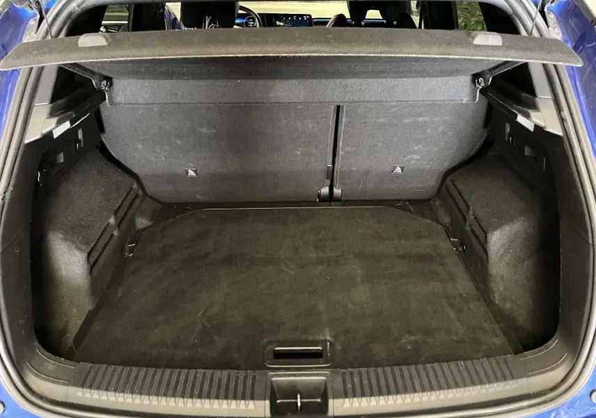 Coffre ouvert vu de l'arrière d'un Renault Austral bleu, montrant l'espace de chargement et la plage arrière.