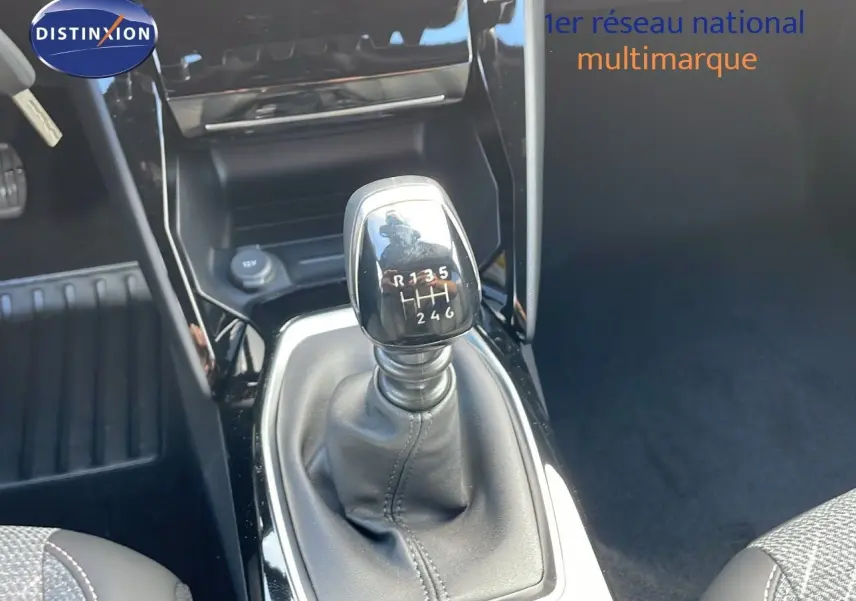 Le levier de vitesses manuel de la Peugeot 2008 gris Artense, avec console noire brillante en intérieur.