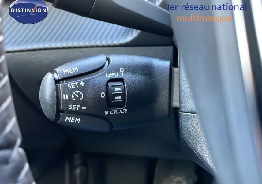 Gros plan sur la commande de régulateur de vitesse à gauche du volant dans un Peugeot 2008 gris Artense Metal.