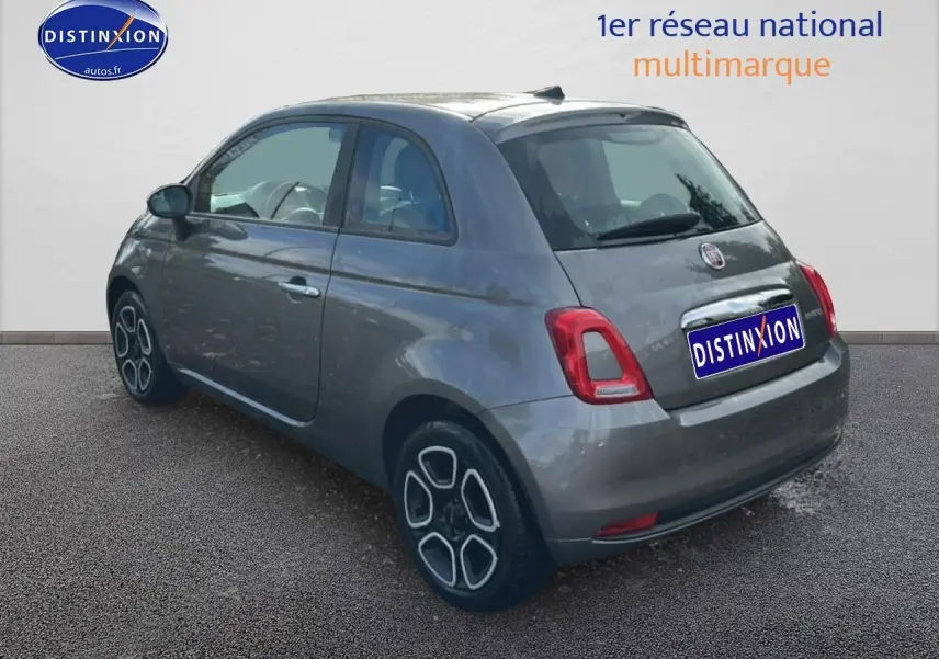 Fiat 500 gris vue 3/4 arrière droit, compacte avec jantes stylisées et feux arrière rectangulaires rouges.