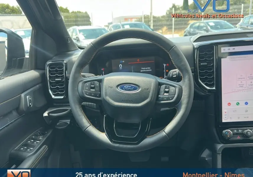 Vue intérieure centrée sur le volant multifonctions du Ford Ranger Wildtrak 2025 avec écran tactile et commandes au volant.