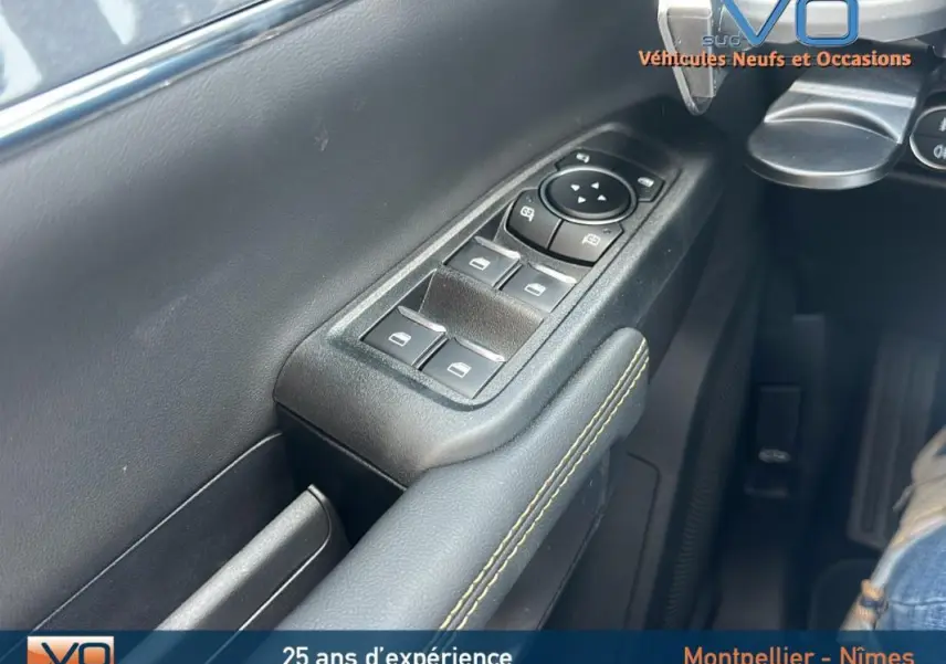 Gros plan sur la commande des vitres électriques côté gauche du Ford Ranger noir, avec surpiqûres jaunes sur l'accoudoir.