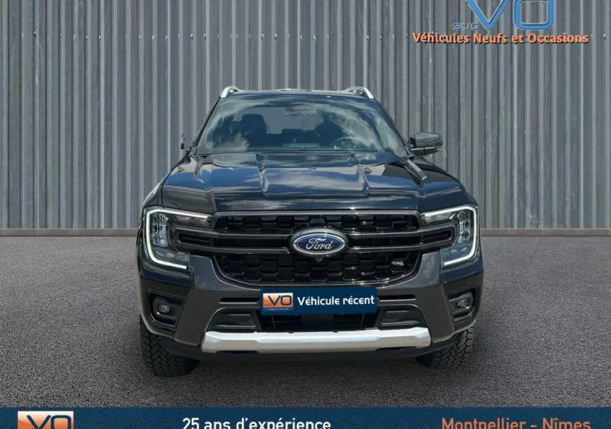 Vue frontale du Ford Ranger Wildtrak noir 2025 avec calandre imposante et barres de toit visibles.