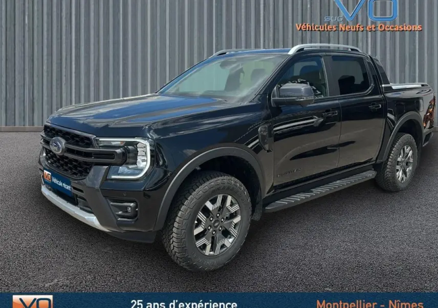 Vue 3/4 avant du Ford Ranger Wildtrak noir 2025 avec barres de toit, marchepieds et jantes alliage 18 pouces.