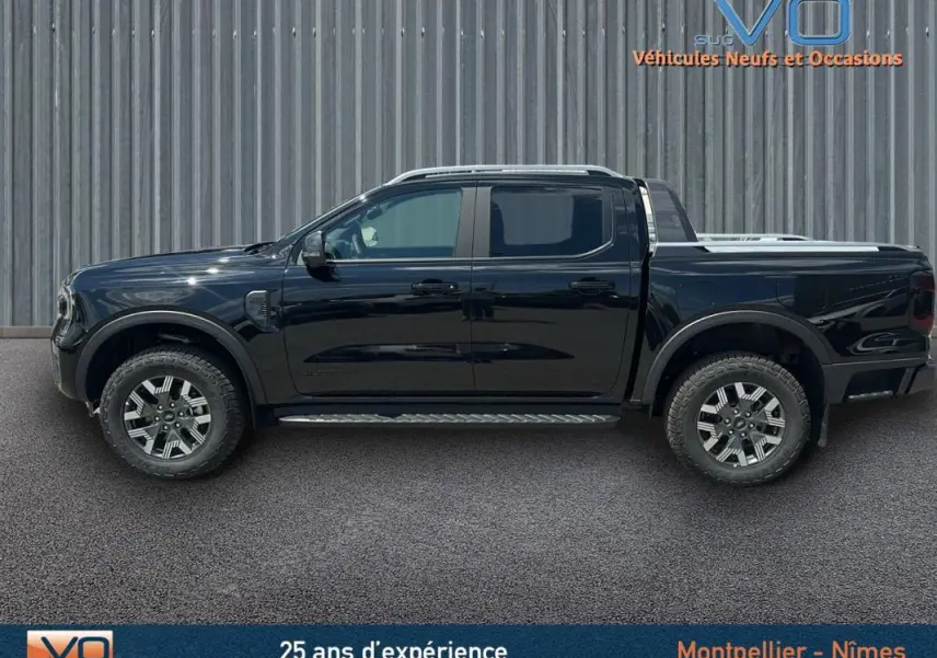 Profil côté gauche du Ford Ranger Wildtrak noir 2025 avec barres de toit, marchepieds et jantes alliage 18 pouces.