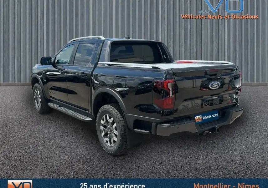 Vue 3/4 arrière côté gauche du Ford Ranger Wildtrak noir avec barres de toit et jantes alliage 18 pouces.