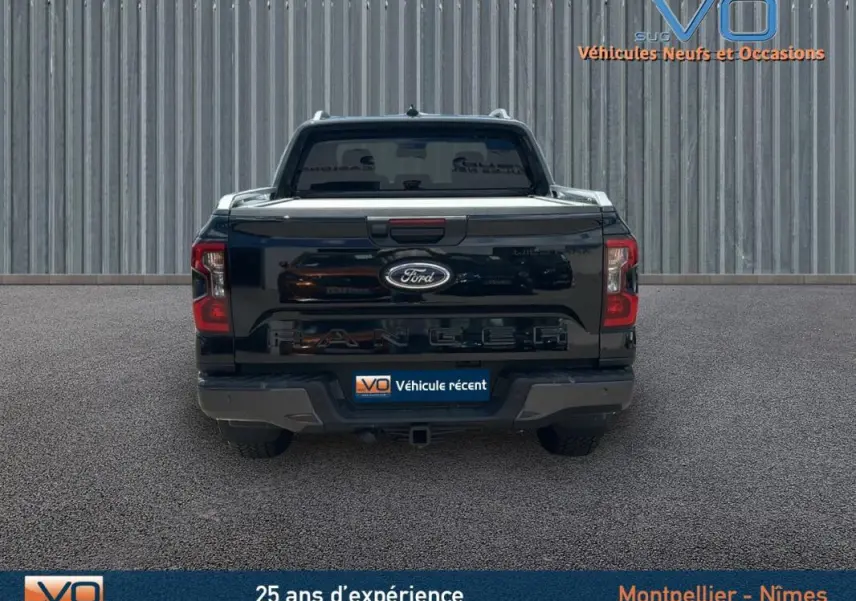 Vue arrière du Ford Ranger Wildtrak noir 2025 avec barres de toit et vitres surteintées visibles.
