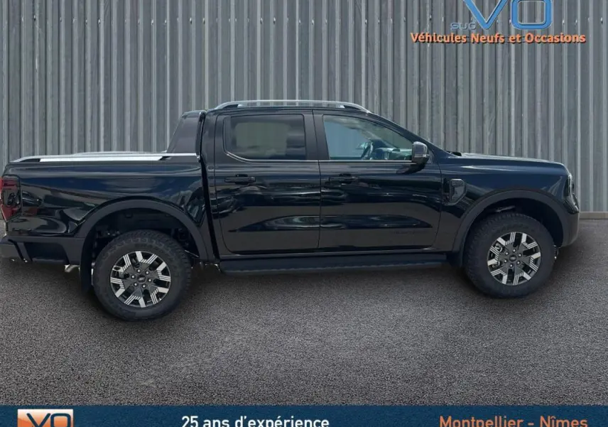Profil côté droit du Ford Ranger Wildtrak 2025 noir avec double cabine, barres de toit et jantes alliage 18 pouces.