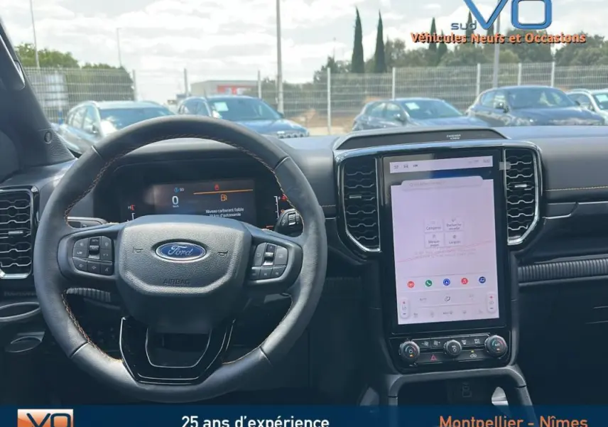Vue intérieure centrée sur le volant multifonctions et l'écran tactile vertical du Ford Ranger Wildtrak noir 2025.