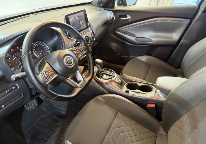 Intérieur Nissan Juke Tekna 2021 vu côté conducteur, volant cuir, console centrale avec écran tactile et sièges noirs.