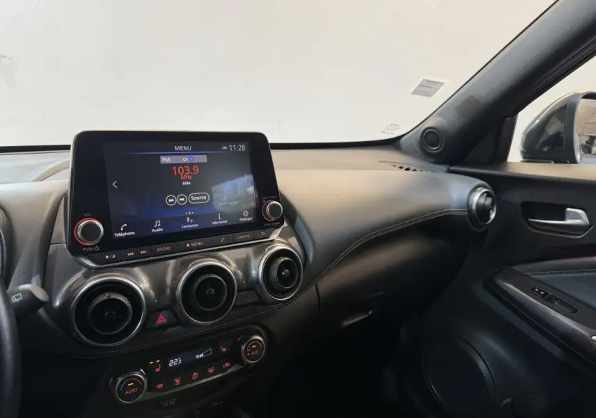 Intérieur du Nissan Juke Tekna 2021 gris clair, vue côté passager sur tableau de bord et écran tactile central.