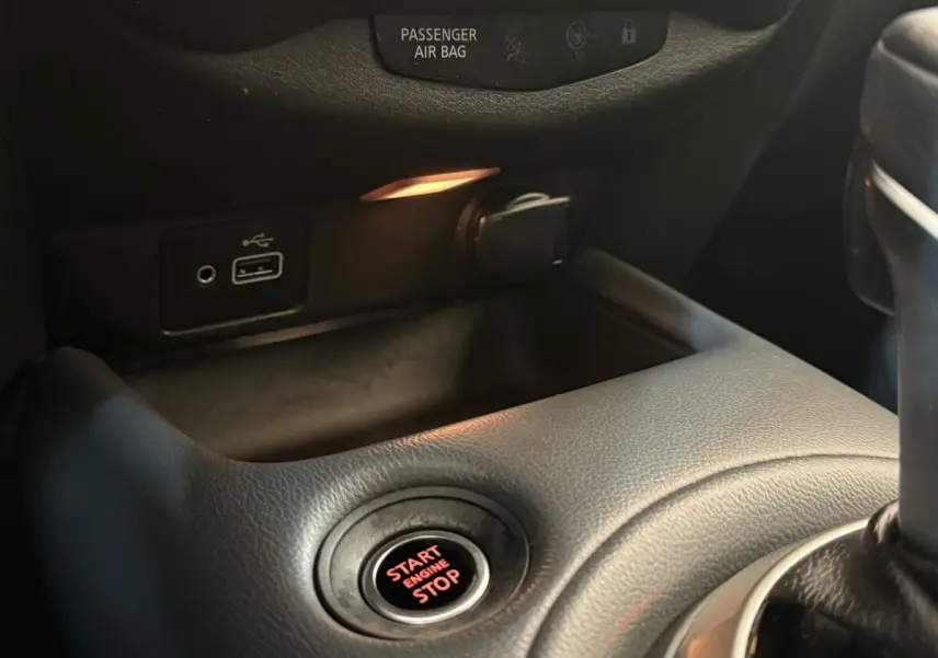 Gros plan sur le bouton démarrage rouge et les ports USB dans l'habitacle noir du Nissan Juke gris clair 2021.