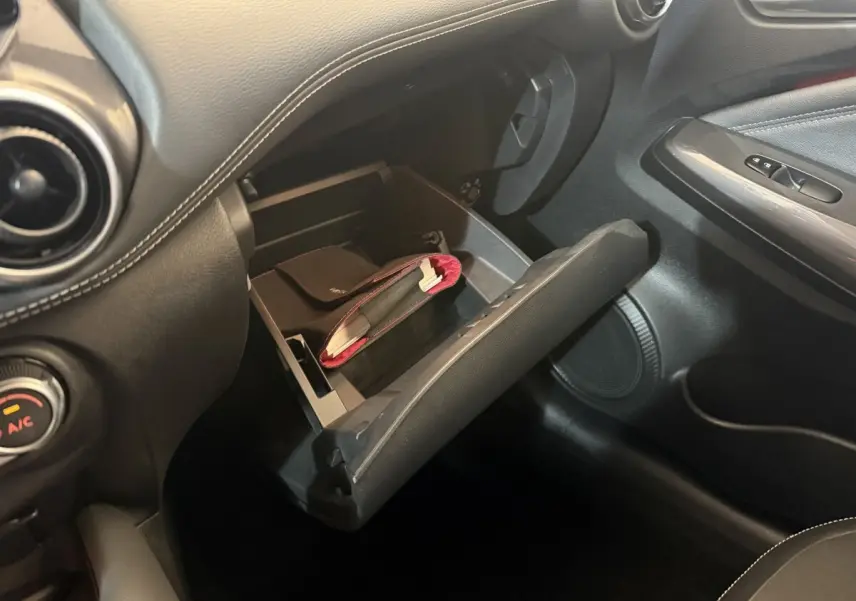 Gros plan sur la boîte à gants ouverte du Nissan Juke Tekna 2021, intérieur noir avec coutures blanches.