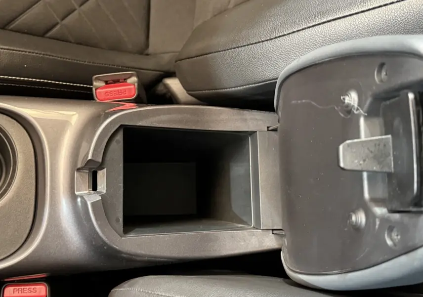 Vue plongeante sur le rangement central ouvert entre les sièges avant en cuir noir du Nissan Juke gris clair.