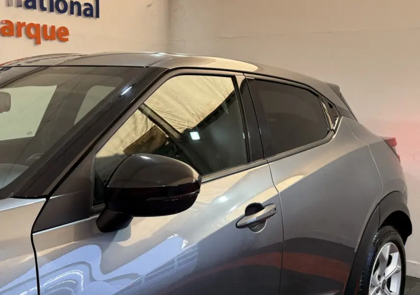 Vue latérale côté gauche d'un Nissan Juke gris clair avec rétroviseur noir et vitres teintées.