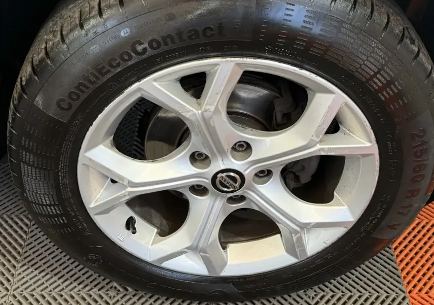 Vue de profil côté gauche d'un Nissan Juke gris clair 2021 avec jantes alliage et pneus hiver visibles.