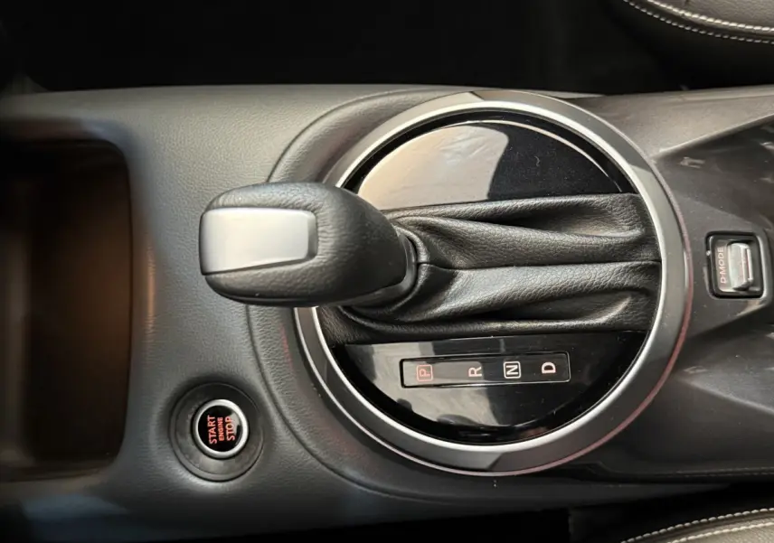 Gros plan sur la commande de boîte automatique et bouton start/stop dans le console centrale d'un Nissan Juke gris clair.
