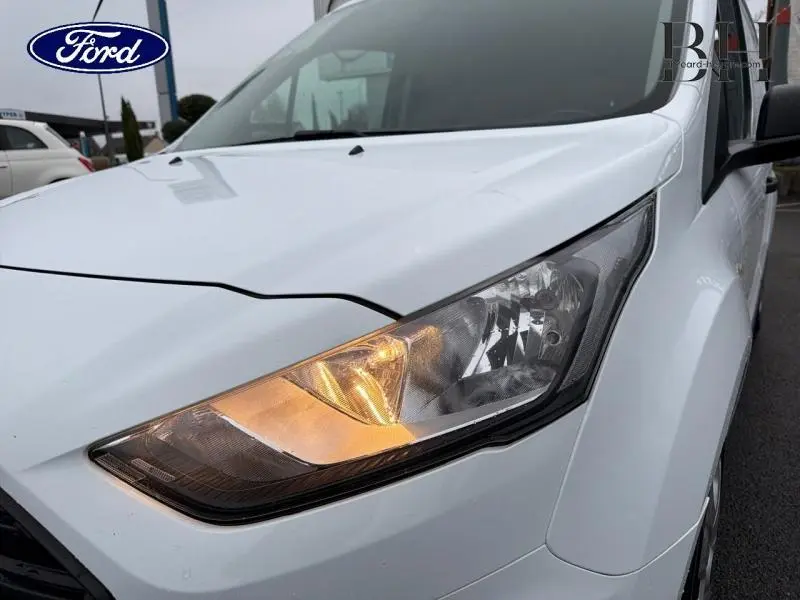 Gros plan sur le phare avant droit allumé du Ford Transit Connect L1 blanc glacier, vue de face côté droit.
